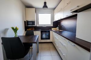 a kitchen with white cabinets and a wooden table at Coldweek apartment - Samorin near X-bionic sphere in Šamorín