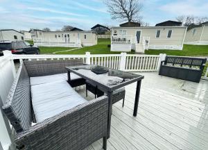 una terraza de madera con una mesa y un banco. en 70 Porth Valley Retreat, en Newquay Bay Resort