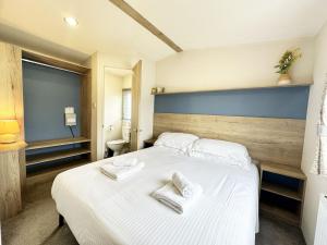 1 dormitorio con 1 cama blanca y 2 toallas en 70 Porth Valley Retreat, en Newquay Bay Resort