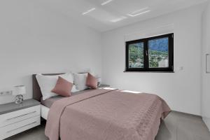 ein weißes Schlafzimmer mit einem Bett und einem Fenster in der Unterkunft Villa Adria in Makarska