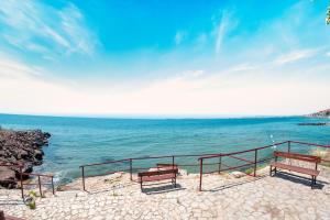 a group of benches sitting next to the ocean at Marina View Fort Beach in Sveti Vlas
