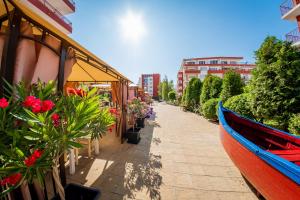 a boat on a sidewalk next to a building with flowers at Marina View Fort Beach in Sveti Vlas
