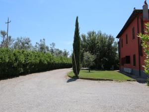 a road next to a red building with a tree at Chic Farmhouse in Montalto di Castro with Terrace in Montalto di Castro