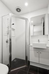 een witte badkamer met een douche en een wastafel bij Convenient Apartment in heart of Carlton in Melbourne
