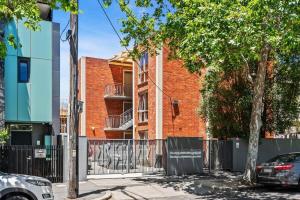 een gebouw van rode baksteen met een hek en bomen bij Convenient Apartment in heart of Carlton in Melbourne
