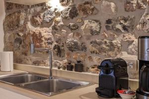 a kitchen with a sink and a stone wall at Casa Antiche Mura in Torri del Benaco