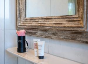 a bathroom shelf with two cups and a mirror at Antares Spiekerooger Gästehaus-Sonnengartenbalkon West - Wohnung 6 in Spiekeroog +8 photos