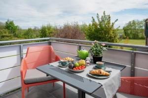 a table and chairs on a balcony with food on it at Antares Spiekerooger Gästehaus-Sonnengartenbalkon West - Wohnung 6 in Spiekeroog