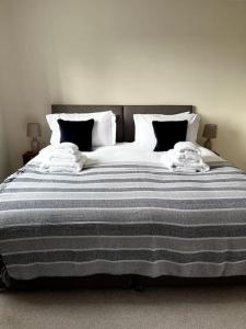 a large bed with a blue and white striped blanket at Bright flat Chichester in Lavant