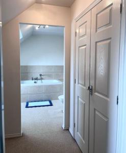 a bathroom with a tub and a toilet and a door at Bright flat Chichester in Lavant