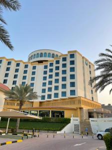 a large building with palm trees in front of it at Oceanic Khorfakkan Resort & Spa in Khor Fakkan