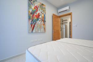 a white bedroom with a painting on the wall at Comfort Lounge Loft - W/1BR in Sliema