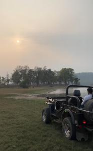 an old car parked in a field with a couple at Wild Woods Tiger Resort in Nagpur