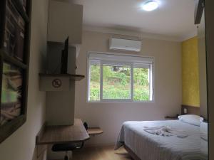 um pequeno quarto com uma cama e uma janela em Adoro Hotel em Farroupilha