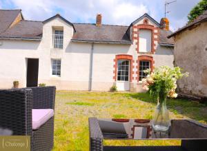 un jarrón de flores en una mesa frente a una casa en L'éco-Domaine du Chalonge en Héric