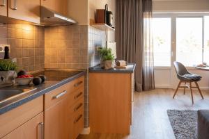 a kitchen with wooden cabinets and a counter top at Antares Spiekerooger Gästehaus-Sonnengartenbalkon Nord - Wohnung 5 in Spiekeroog +7 photos