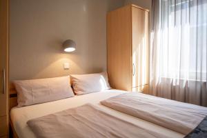 a bedroom with a white bed with a window at Antares Spiekerooger Gästehaus-Sonnengartenbalkon Nord - Wohnung 5 in Spiekeroog