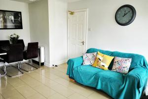 um sofá azul numa sala de estar com um relógio na parede em The Sandhills, Tramore Beach em Tramore