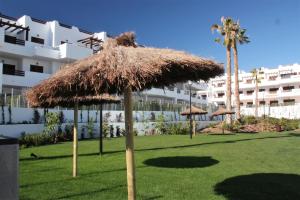 a large straw umbrella in a field in front of a building at Casa del sur in San Juan de los Terreros