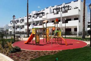 um parque infantil em frente a um grande edifício em Casa del sur em San Juan de los Terreros