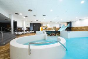bañera grande en una habitación con mesas y sillas en Atrium Hotel - Family friendly, en Starý Smokovec