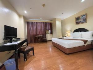 Golden Peak Hotel & Suites powered by Cocotel في مدينة سيبو: غرفة في الفندق بها سرير ومكتب وبه جهاز كمبيوتر