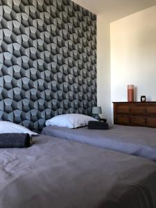 a bedroom with two beds and a wall with a headboard at Votre oasis de détente : Appartement flambant neuf, 1 chambre, 4 couchages à Aubigné-racan in Aubigné-Racan
