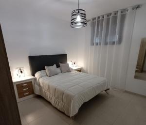 biała sypialnia z łóżkiem i lampką w obiekcie Vandelvira 2 w mieście Baeza