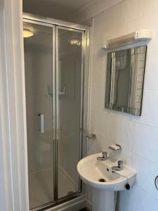 a bathroom with a sink and a glass shower at Cunard Guest House in Weymouth