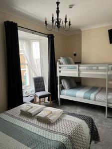 a bedroom with two bunk beds and a chair at Cunard Guest House in Weymouth