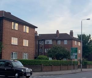 un coche negro estacionado frente a un edificio de ladrillo en Beddington Park Lodge West en Wallington