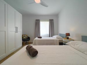 a white bedroom with two beds and a ceiling fan at 21 Townhouse in St Julians in Paceville