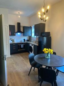Dublin City Centre Apartment في دبلن: مطبخ مع طاولة وكراسي ومطبخ مع دواليب سوداء