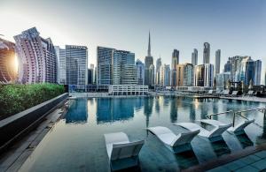 uma piscina com cadeiras brancas e um horizonte da cidade em Gennaro´s home at 15 Northside Business Bay em Dubai