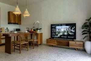 a living room with a television and a kitchen at Sunny Cuddles in Canggu
