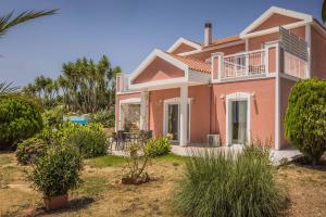 a pink house with trees and plants in a yard at Villa Marita in Spathíon