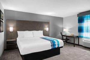 a hotel room with a large bed and a desk at La Quinta Inn by Wyndham Indianapolis Airport Executive Dr in Indianapolis