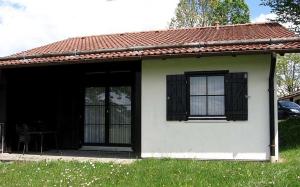 Casa blanca pequeña con ventanas negras y mesa en Ferienhaus Nr 6, Kategorie Königscard, Feriendorf Hochbergle, Allgäu, en Bichel