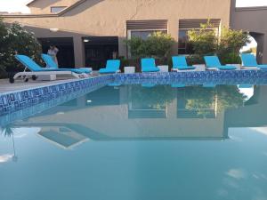 a swimming pool with blue lounge chairs next to a house at Ein Gedi Premier Weddings And Conferences in Kimberley