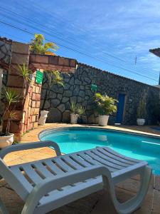 Una piscina con un banco al lado de una casa. en Hotel Santa Clara, en Caldas Novas