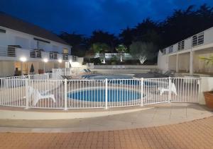 a white fence around a swimming pool at night at RÉSID'AZUR APPARTEMENT T2-PMR- Piscine privée in Saint-Jean-de-Monts