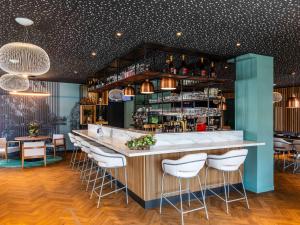 - un bar avec tabourets de bar blanc dans un restaurant dans l'établissement Mercure Saint Omer Centre Gare, à Saint-Omer