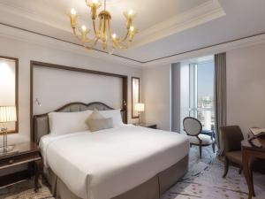 a bedroom with a large white bed and a chandelier at Raffles Makkah Palace in Makkah