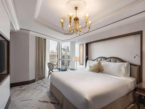 a bedroom with a large white bed and a chandelier at Raffles Makkah Palace in Mecca