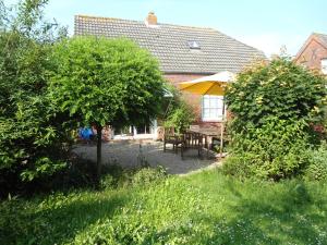 a garden with a table and a yellow umbrella at Campen Cottage in Krummhörn