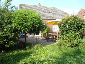 - un jardin avec une table et un parasol jaune dans l'établissement Campen Cottage, à Krummhörn