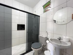 a bathroom with a toilet and a sink and a mirror at Pousada Praia da Cueira in Cayru