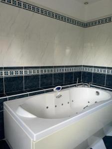 y baño con bañera blanca y azulejos negros. en Maison Le Perreux sur marne 4 chambres, en Le Perreux-Sur-Marne