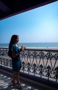 a woman standing on a balcony looking at the ocean at Regenta Central Puri Odisha in Puri