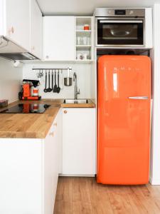 an orange refrigerator in a kitchen with white cabinets at La Petite bohéme with free parking in Stockholm